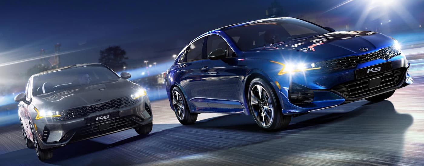 A grey and a blue 2025 Kia K5 from the front.